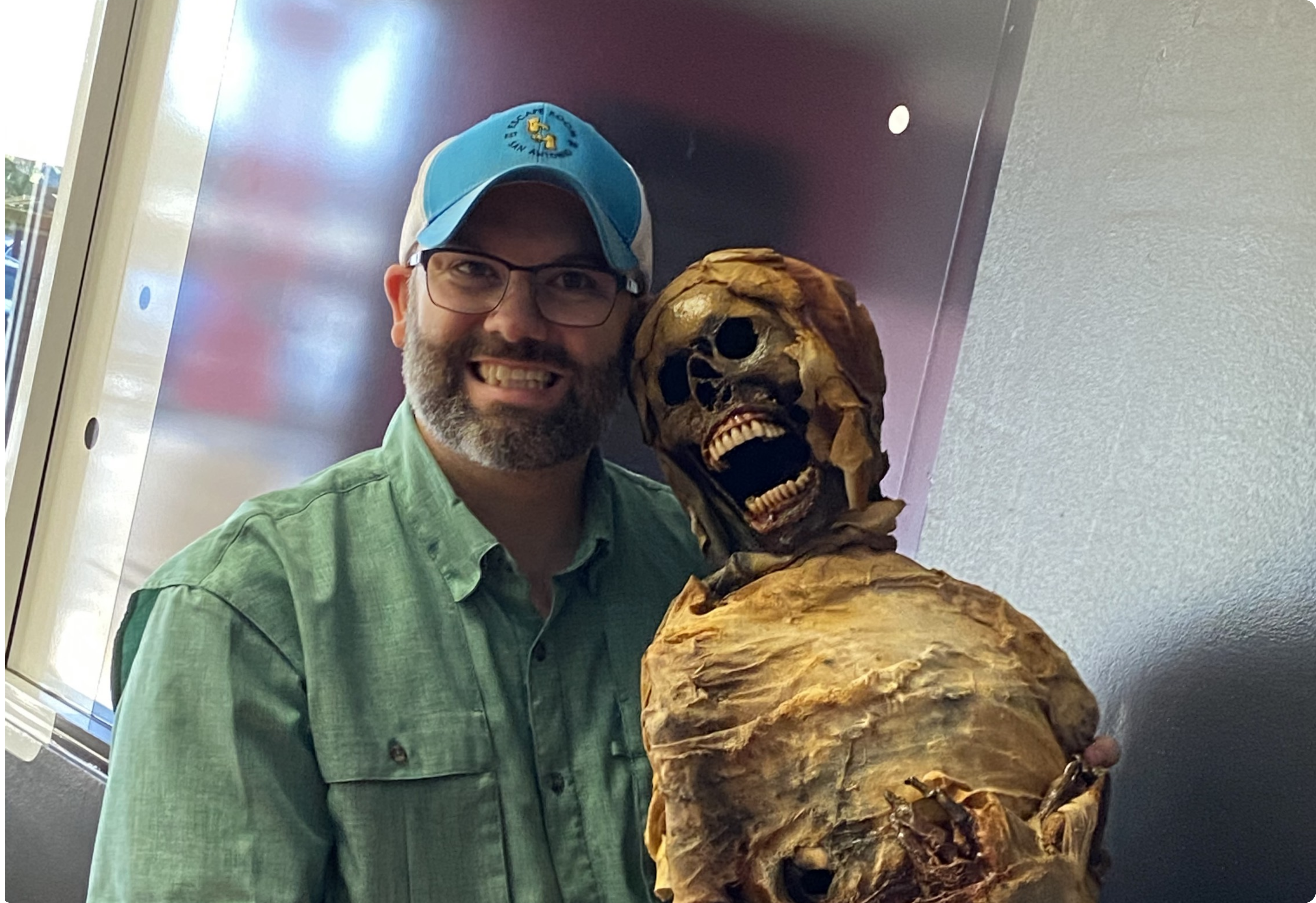 Photo of Tyler Dahl holding a prop mummy and smiling