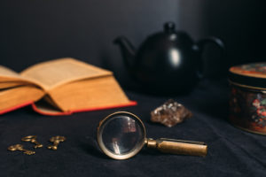 magnifying glass, book, and tea pot laid out on a table | 5 Things to Know About Escape Room SA in Stone Oak